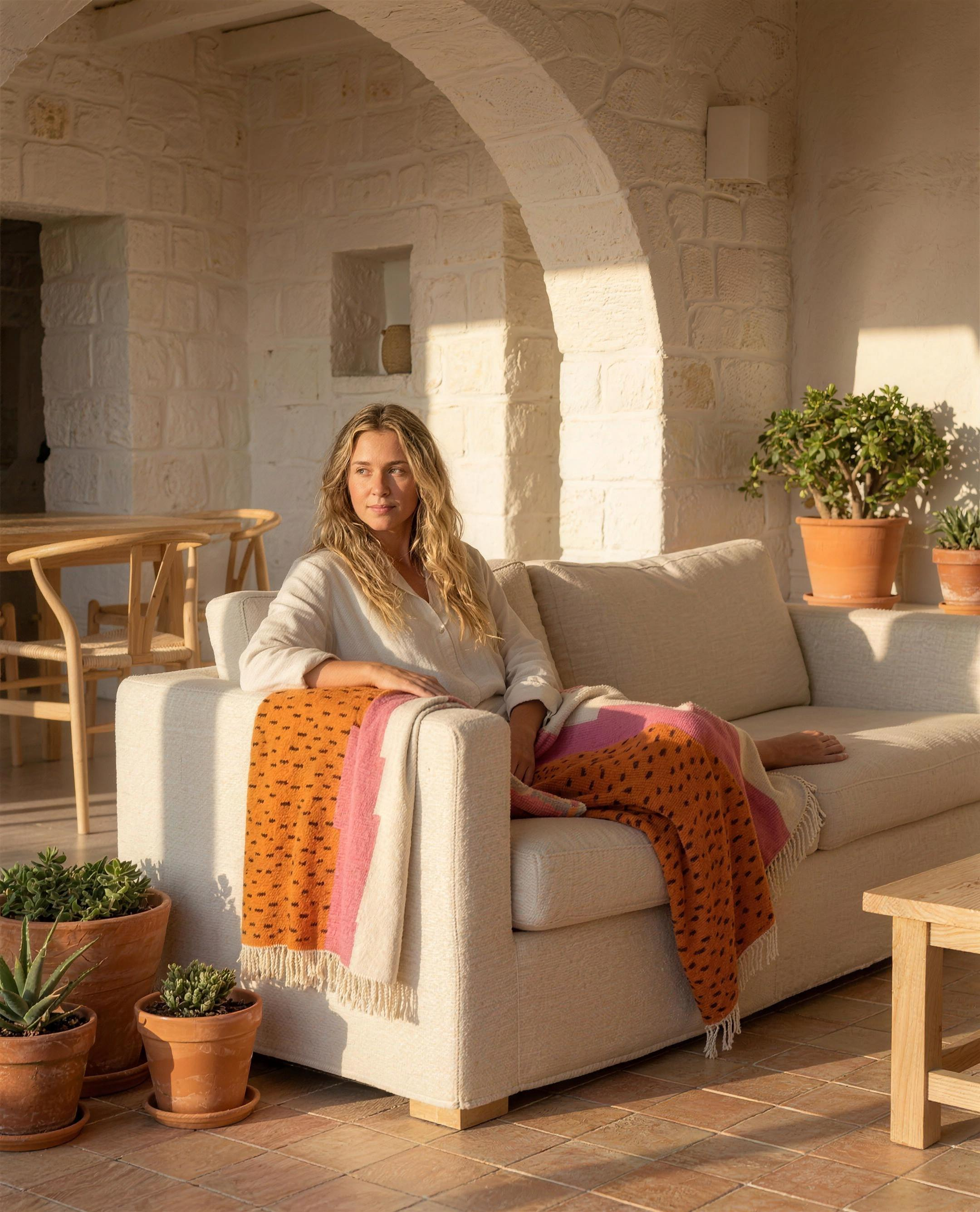 Woman relaxing on a linen sofa with the Atlas Berber throw blanket