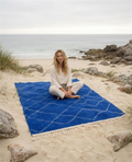 Woman sitting on the blue Beni Ouarain Berber throw on a Breton beach